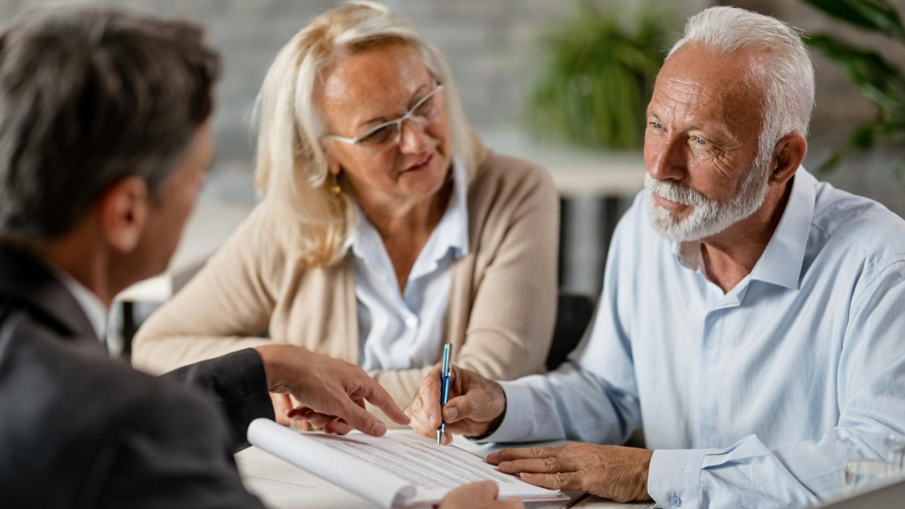 mature-couple-having-meeting-with-bank-manager-signing-lease-agreement-office-focus-is-mature-man